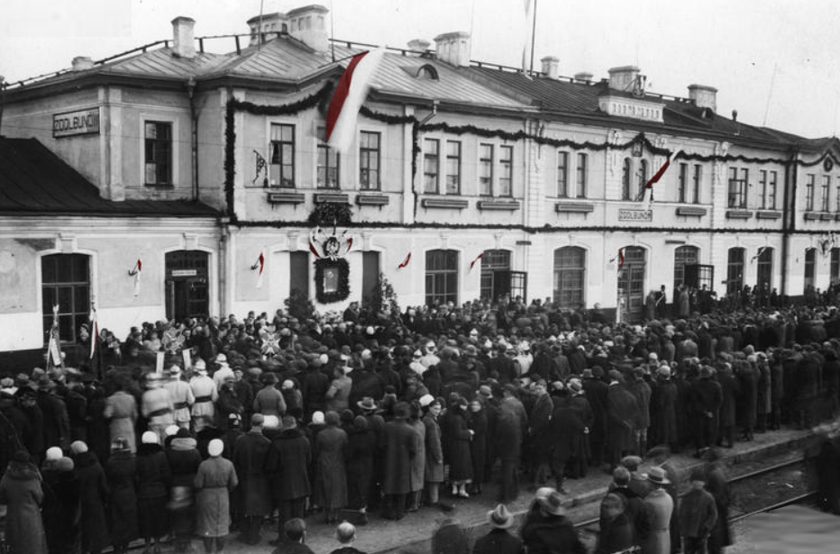 Tłum ludzi przed budynkiem stacji w Zdołbunowie w 1934 roku podczas uroczystości odsłonięcia tablicy pamiątkowej ku czci marszałka Józefa Piłsudskiego.