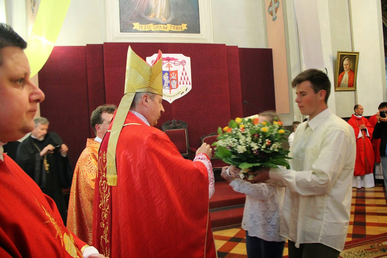 Biskup Piotr Malczuk przyjmuje w darze kawiaty od młodzieży